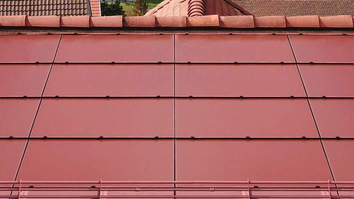 Rotes Dach mit großen, flachen Ziegeln und sichtbaren Metallbefestigungen, von oben gesehen. - © Swisspearl Swisspearl expands its module line with a new brick-red colour option